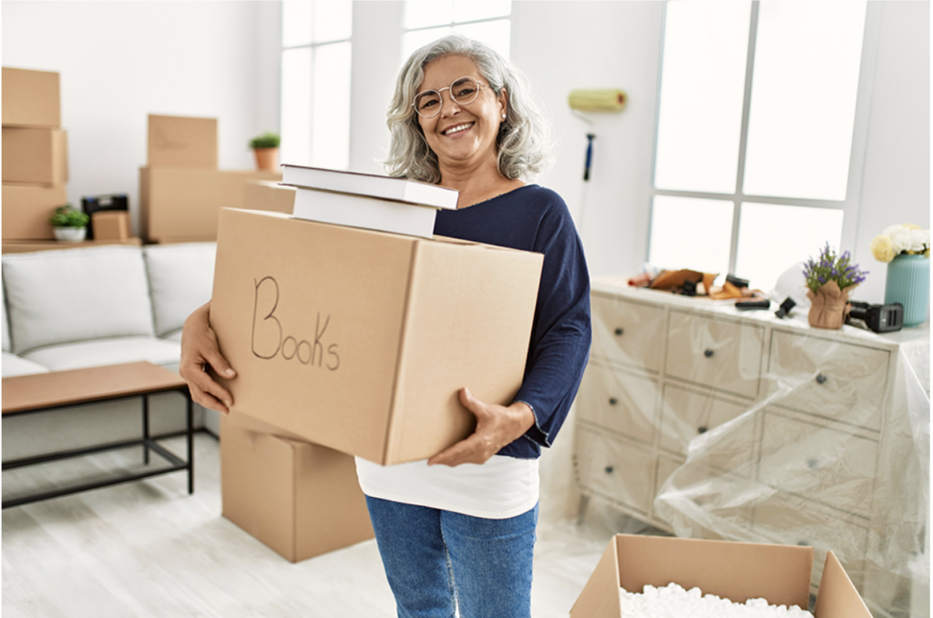 A smiling Boca Raton senior woman holding a moving box